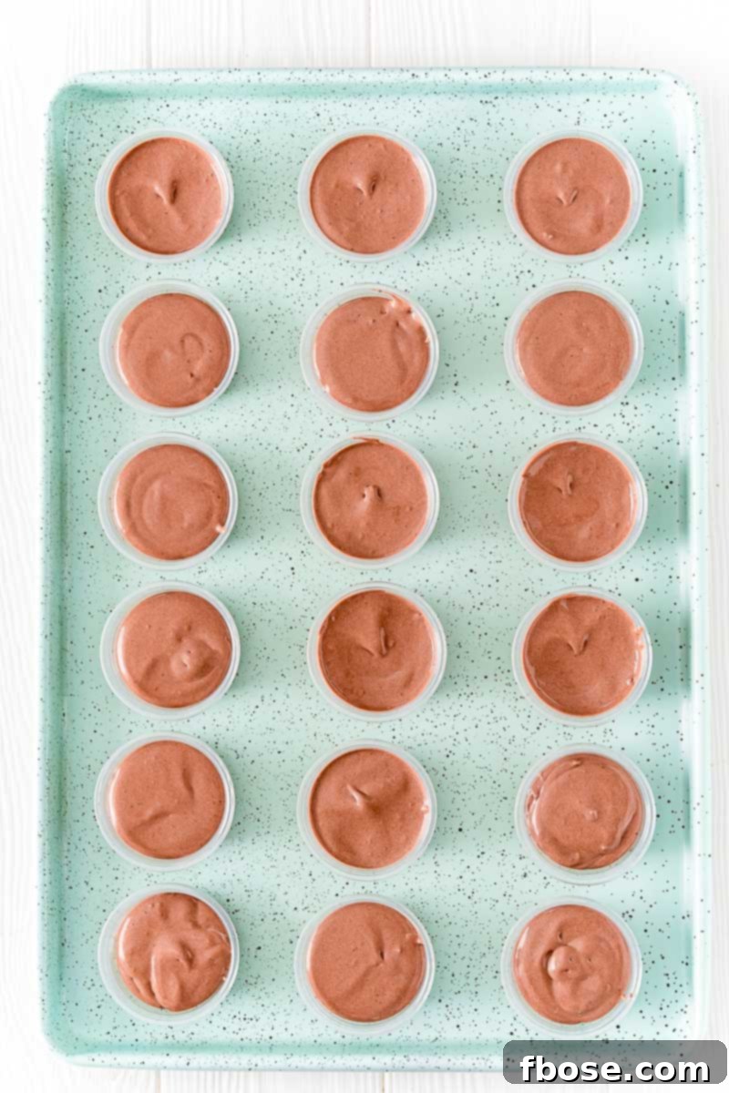Overhead photo of a batch of creamy pudding shots arranged neatly on a light blue cookie sheet, ready for serving.
