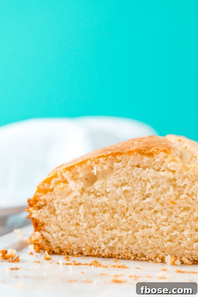 A freshly baked loaf of Ice Cream Bread, expertly sliced, is presented on a clean white cutting board, inviting a taste.