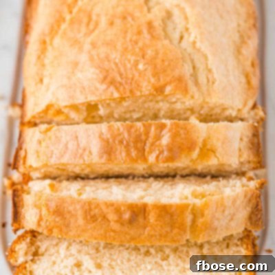 Loaf of bread on a white cutting board partially sliced.