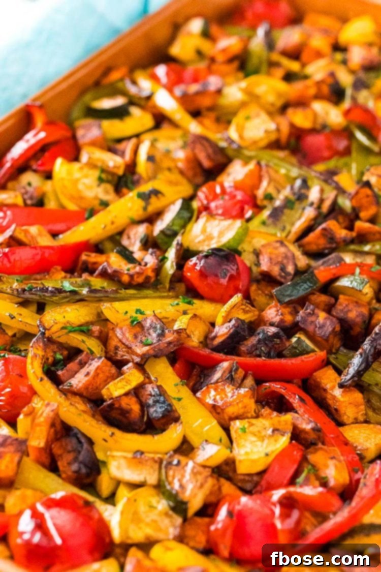 A vibrant medley of oven-roasted vegetables, including sweet potatoes, bell peppers, zucchini, and cherry tomatoes, perfectly caramelized and ready to serve on a sheet pan.