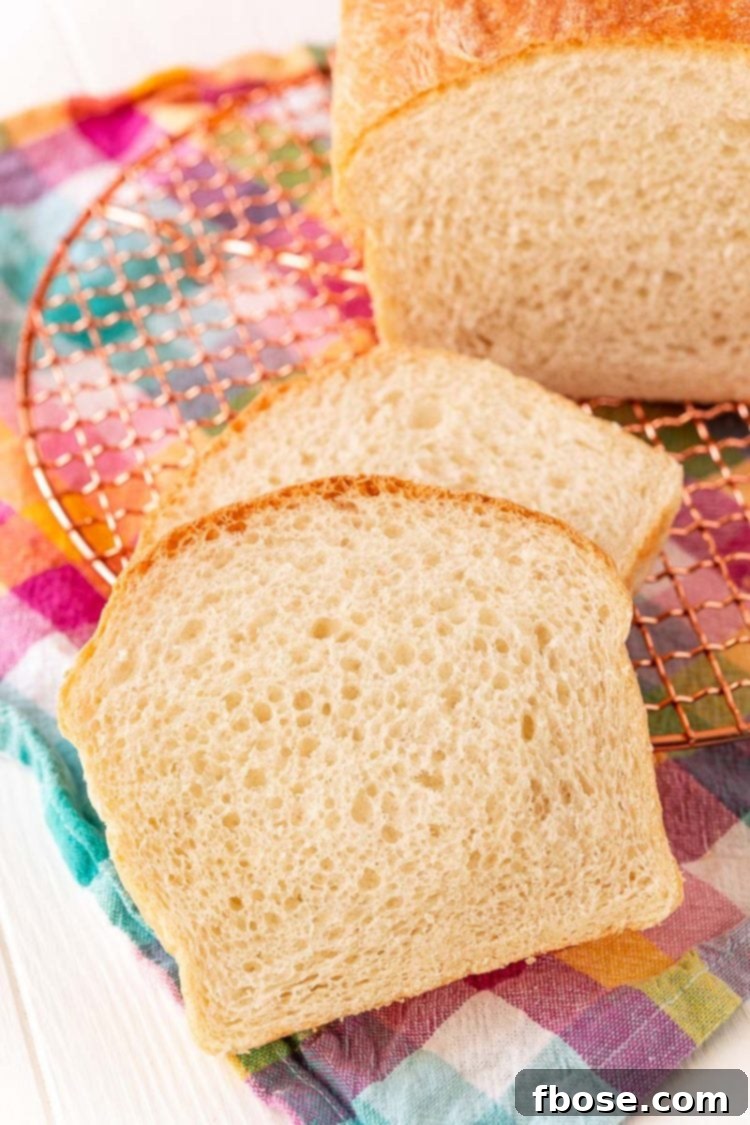 Close-up of freshly baked, perfectly sliced white bread arranged artfully on a colorful patterned napkin, showcasing its fluffy texture.