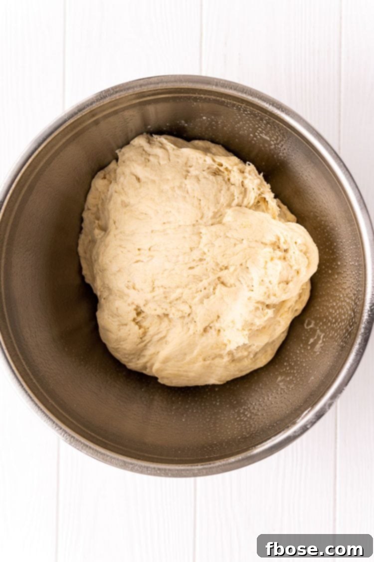 Smooth, elastic bread dough resting in a large metal bowl, lightly greased and ready for its first rise.