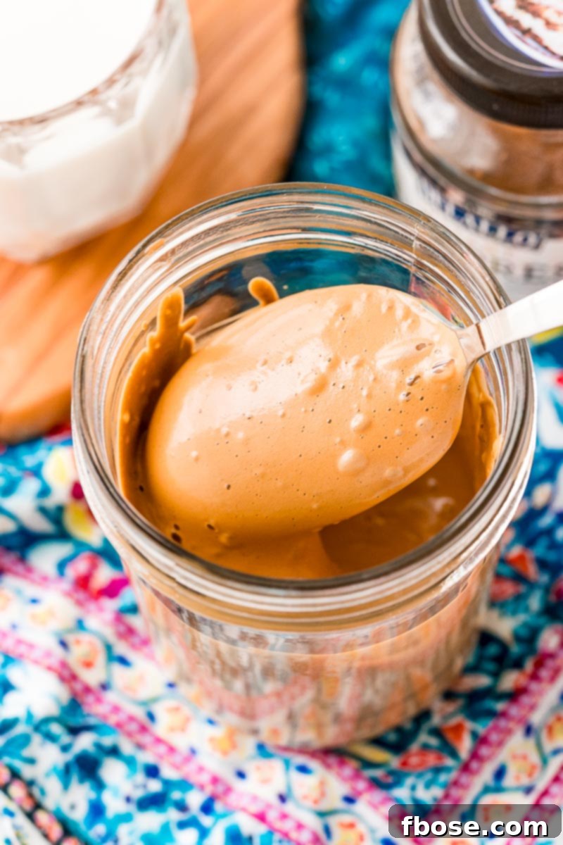 A spoon coming out of a mason jar with whipped coffee on it.