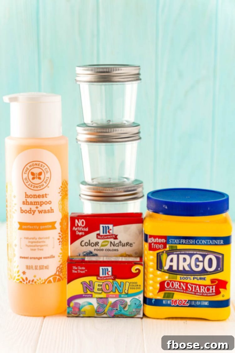 Ingredients for making kids bath paint laid out on a white table: cornstarch, baby shampoo, and food coloring.