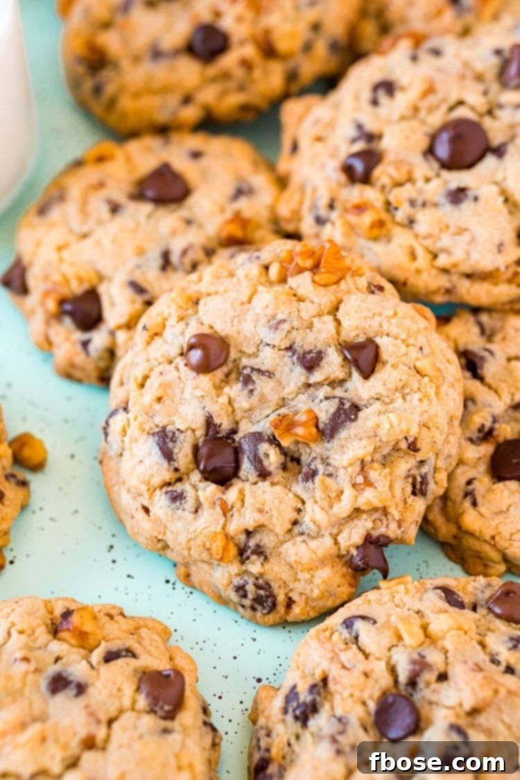 Chocolate chip walnut cookies piled on top of each other, showcasing their generous size and tempting texture.