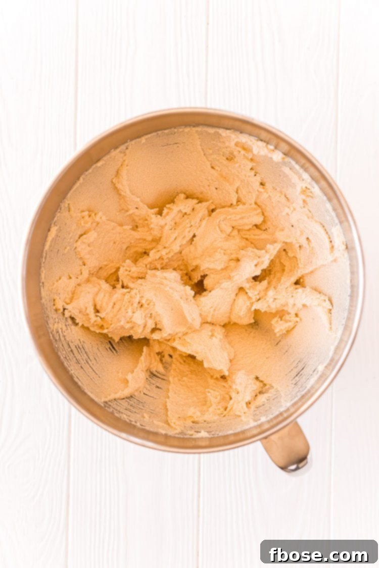 Butter and sugar thoroughly creamed together in a stand mixer bowl, showing a pale, fluffy consistency.
