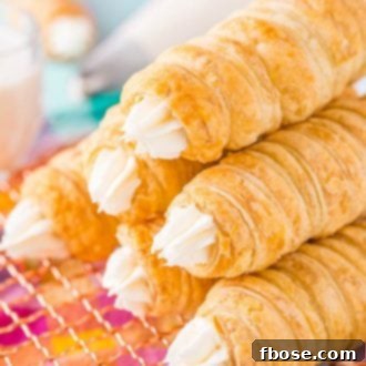 Six cream horns stacked on top of each other on a wire rack.