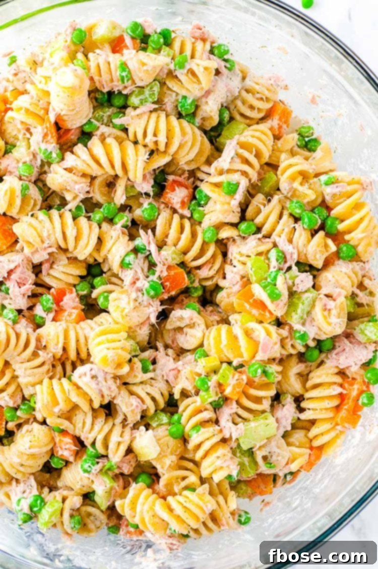 Overhead photo of tuna pasta salad in a clear glass bowl, showcasing the vibrant ingredients.