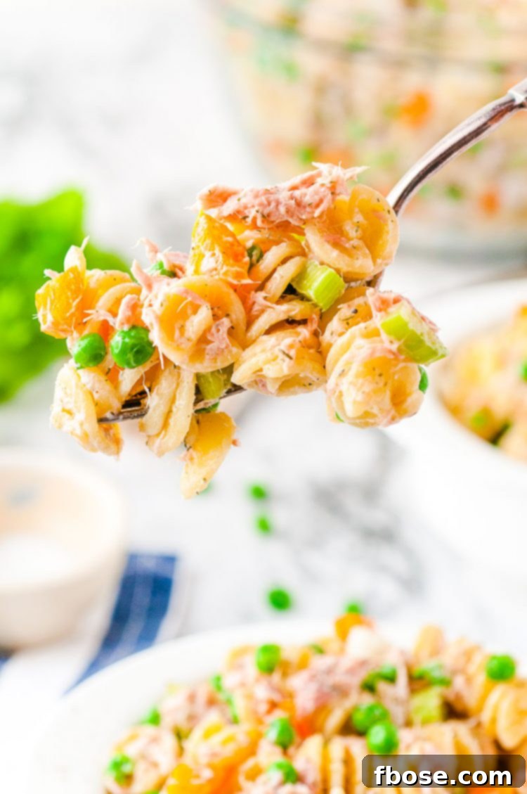 A fork full of creamy tuna pasta salad, showing the mixed ingredients.