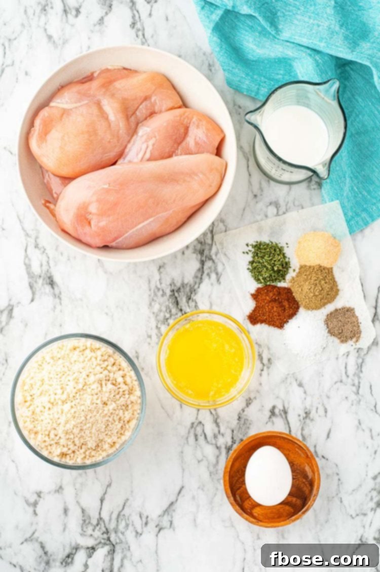 Fresh ingredients laid out on a marble countertop, ready to prepare breaded baked chicken.