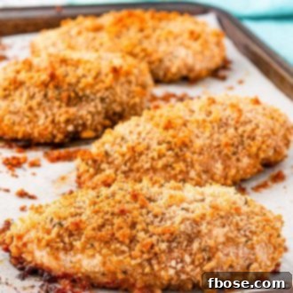 Baked chicken breast on a sheet pan that's been breaded.