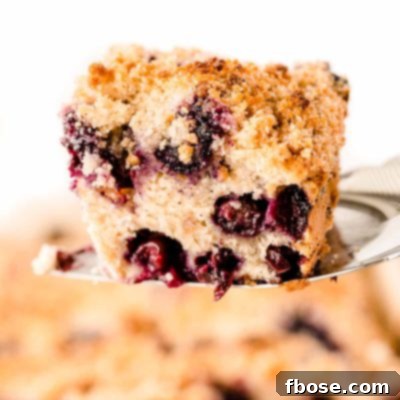 A spatula lifting a slice of blueberry buckle out of the pan.