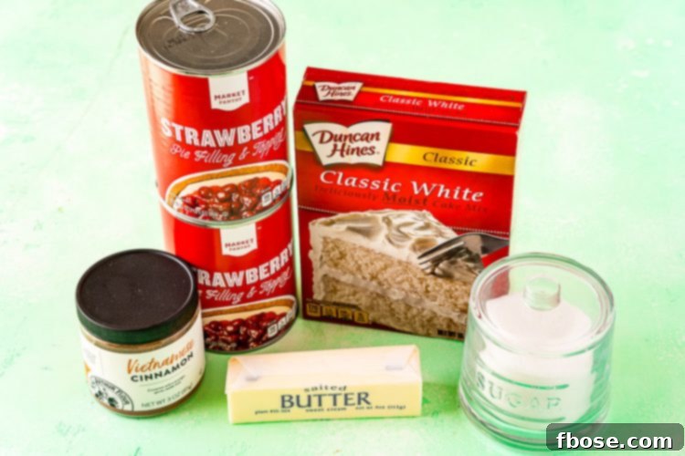 A collection of essential ingredients for making strawberry cobbler, including canned strawberry pie filling, a box of yellow cake mix, and sticks of butter, neatly arranged on a rustic wooden surface.