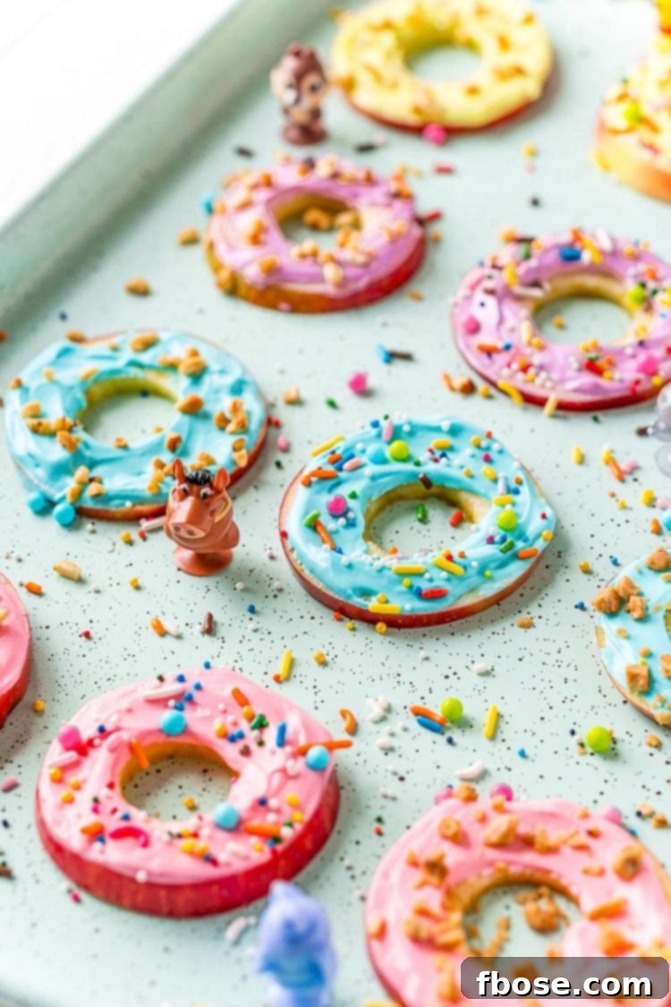 A serving tray filled with beautifully frosted apple donut slices, each adorned with colorful sprinkles, presented on a vibrant blue background.