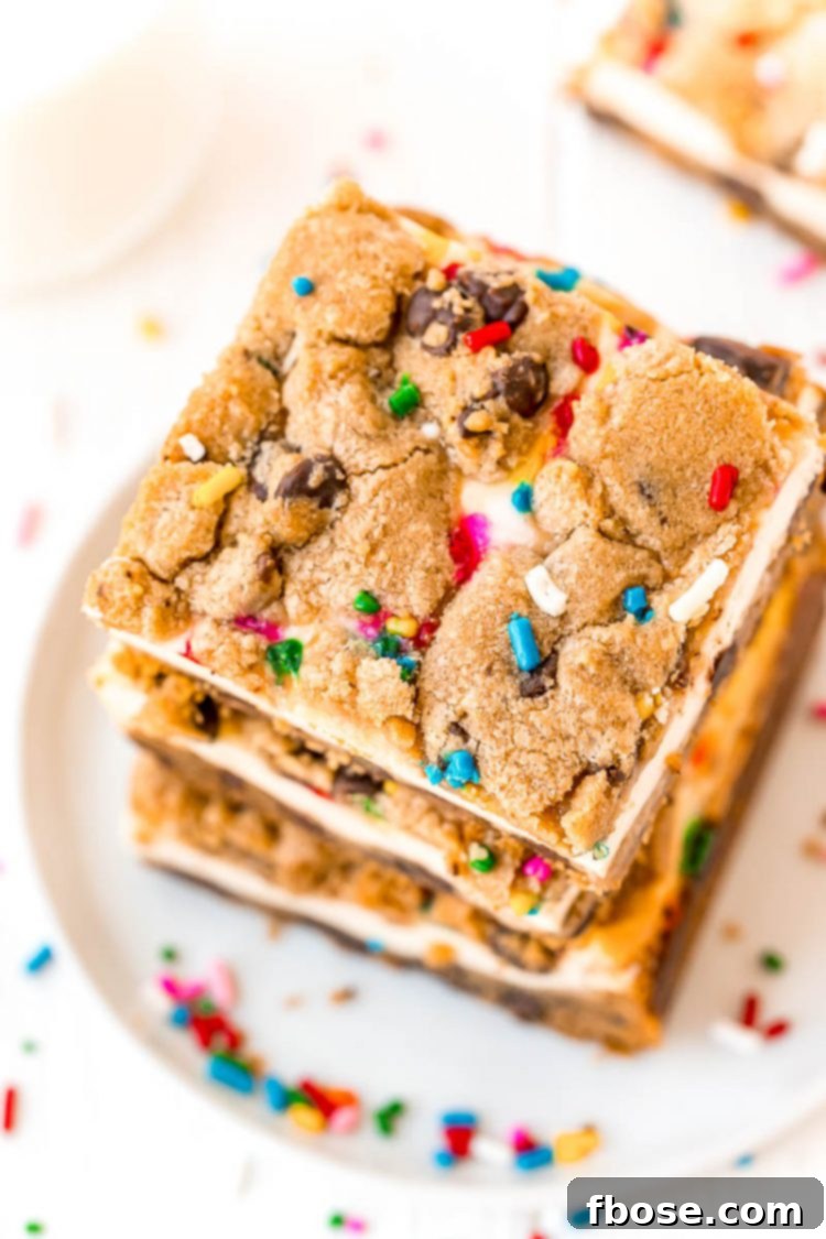 Overhead photo of a stack of neatly cut chocolate chip cheesecake squares on a white plate, surrounded by colorful sprinkles, showcasing the layers.
