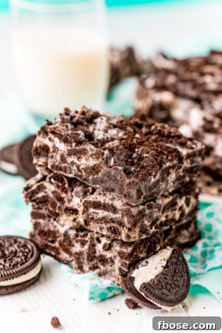 Three marshmallow oreo treats stacked on top of each other on a teal napkin.