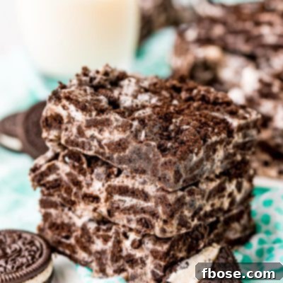 Three marshmallow oreo treats stacked on top of each other on a teal napkin.