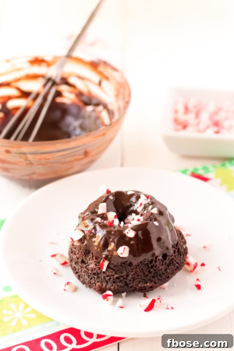 A close-up shot of the moist interior of a Mini Chocolate Peppermint Bundt Cake, showcasing its rich dark chocolate crumb, topped with a generous swirl of peppermint whipped cream.