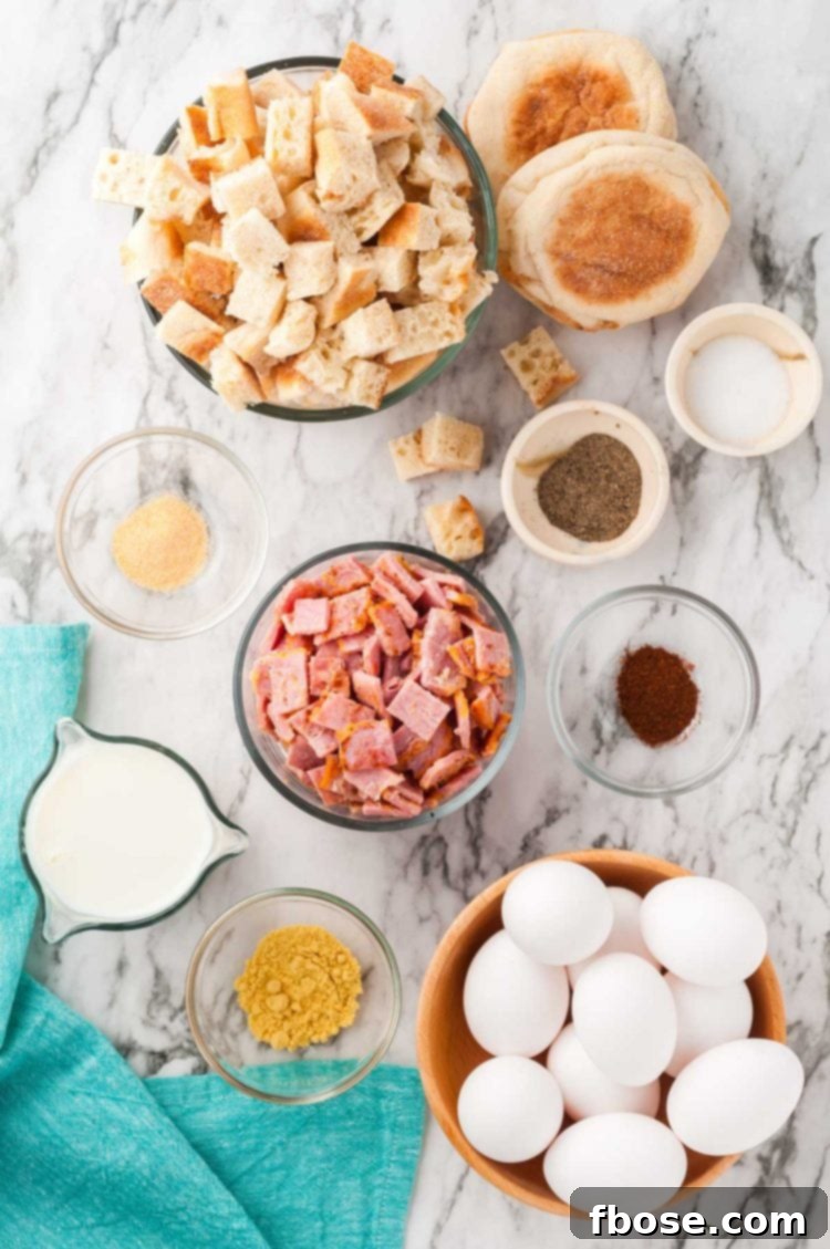 Overhead photo of fresh ingredients laid out, including English muffins, Canadian bacon, eggs, milk, and spices, ready to make breakfast casserole.