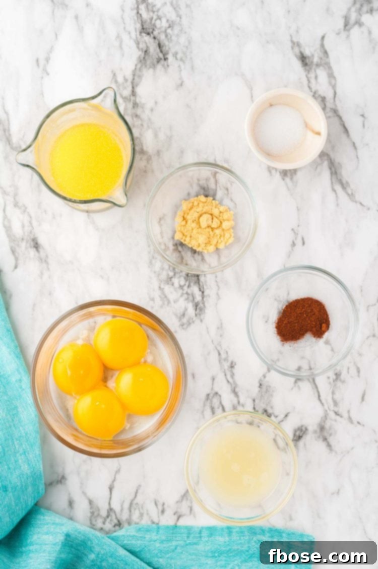 Ingredients meticulously arranged for making Hollandaise sauce, including egg yolks, lemon, butter, and spices.