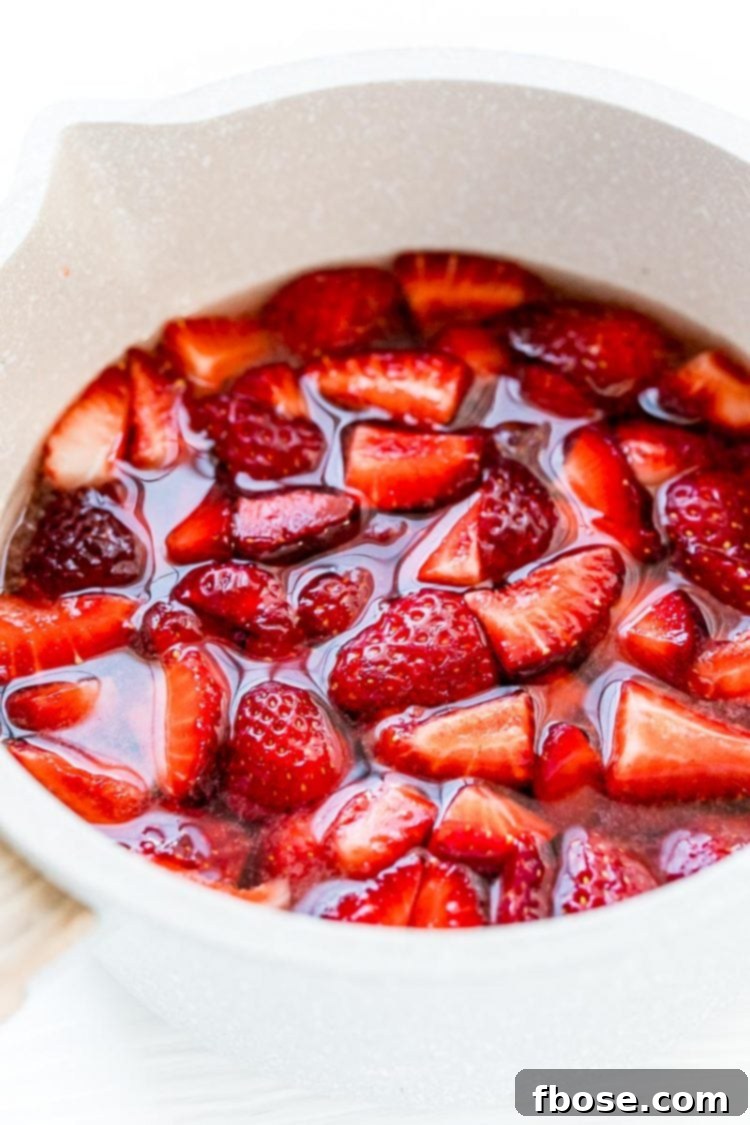 Fresh strawberries simmering in a small pot with other ingredients to create simple syrup.