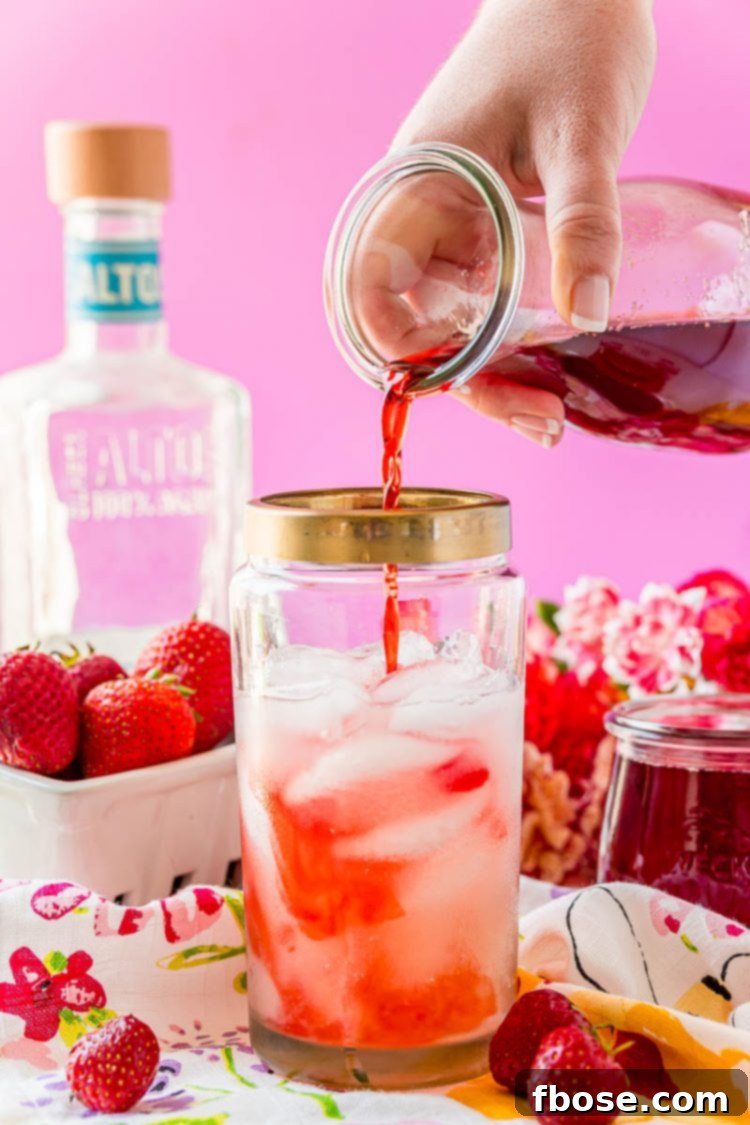 Strawberry simple syrup being poured into a cocktail shaker, ready to mix a delicious drink.