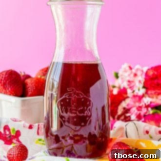 Glass carafe filled with strawberry simple syrup.