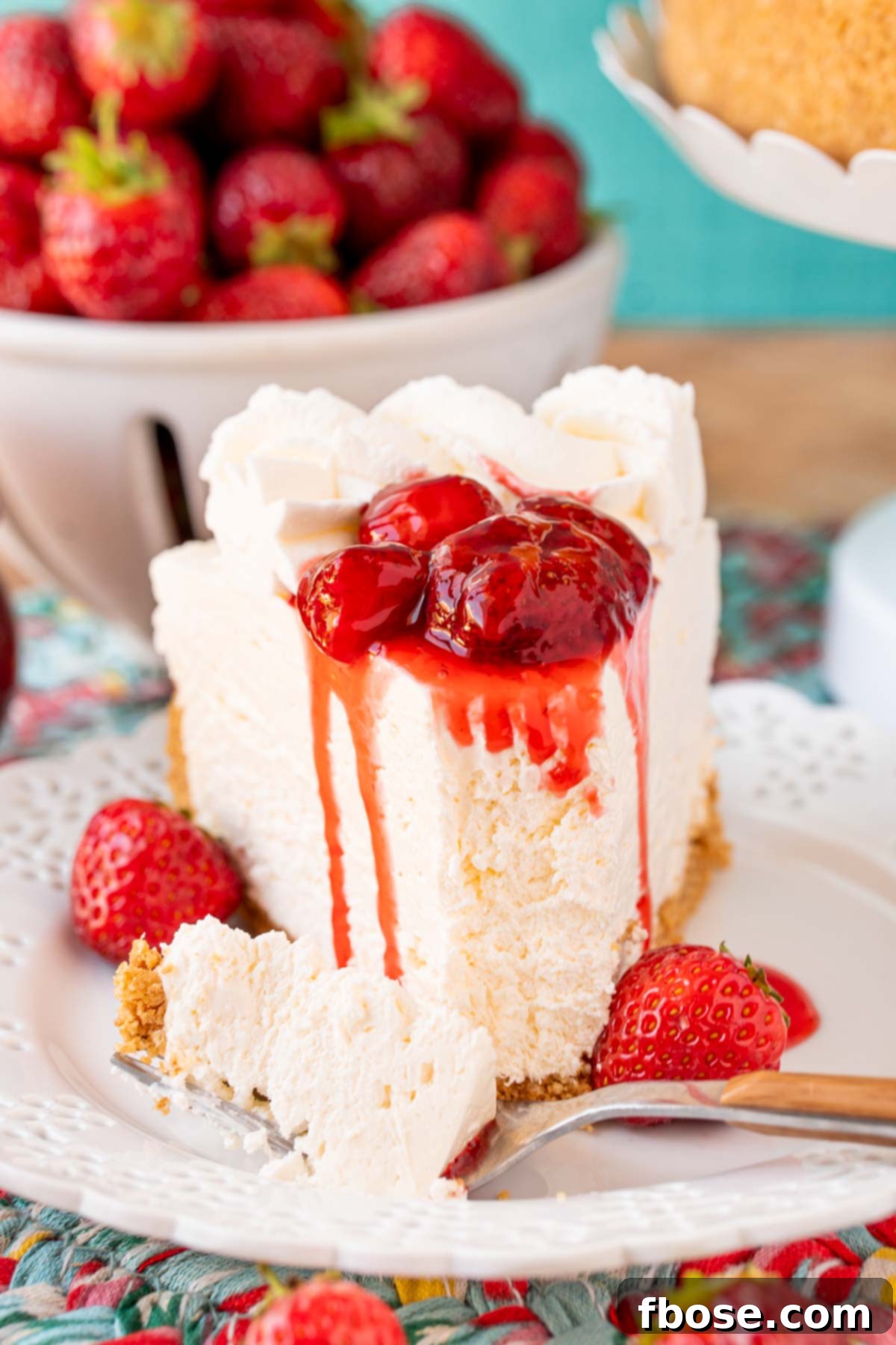A slice of no bake cheesecake on a white plate topped with strawberry sauce.