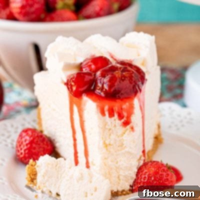 A slice of no bake cheesecake on a white plate topped with strawberry sauce.