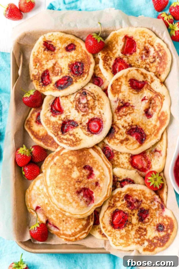Overhead photo of a baking sheet with strawberry pancakes on it.