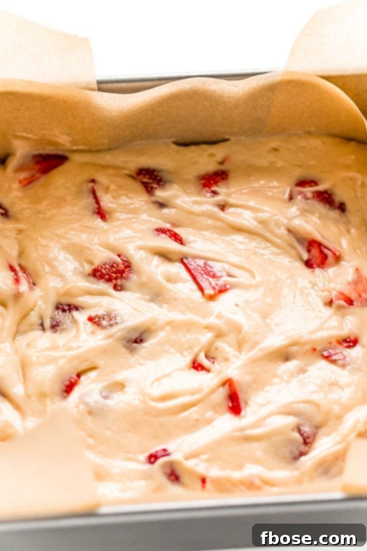 Strawberry cake in a parchment lined baking dish.