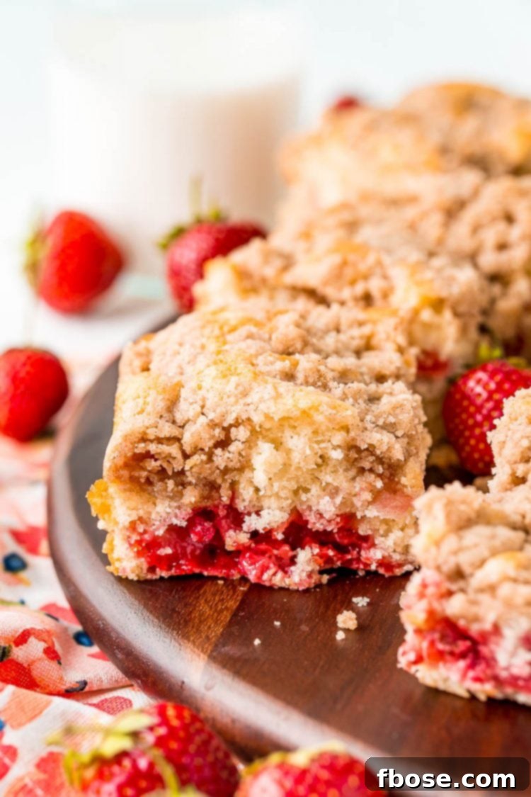Slices of strawberry coffee cake sitting on a wooden cutting board.