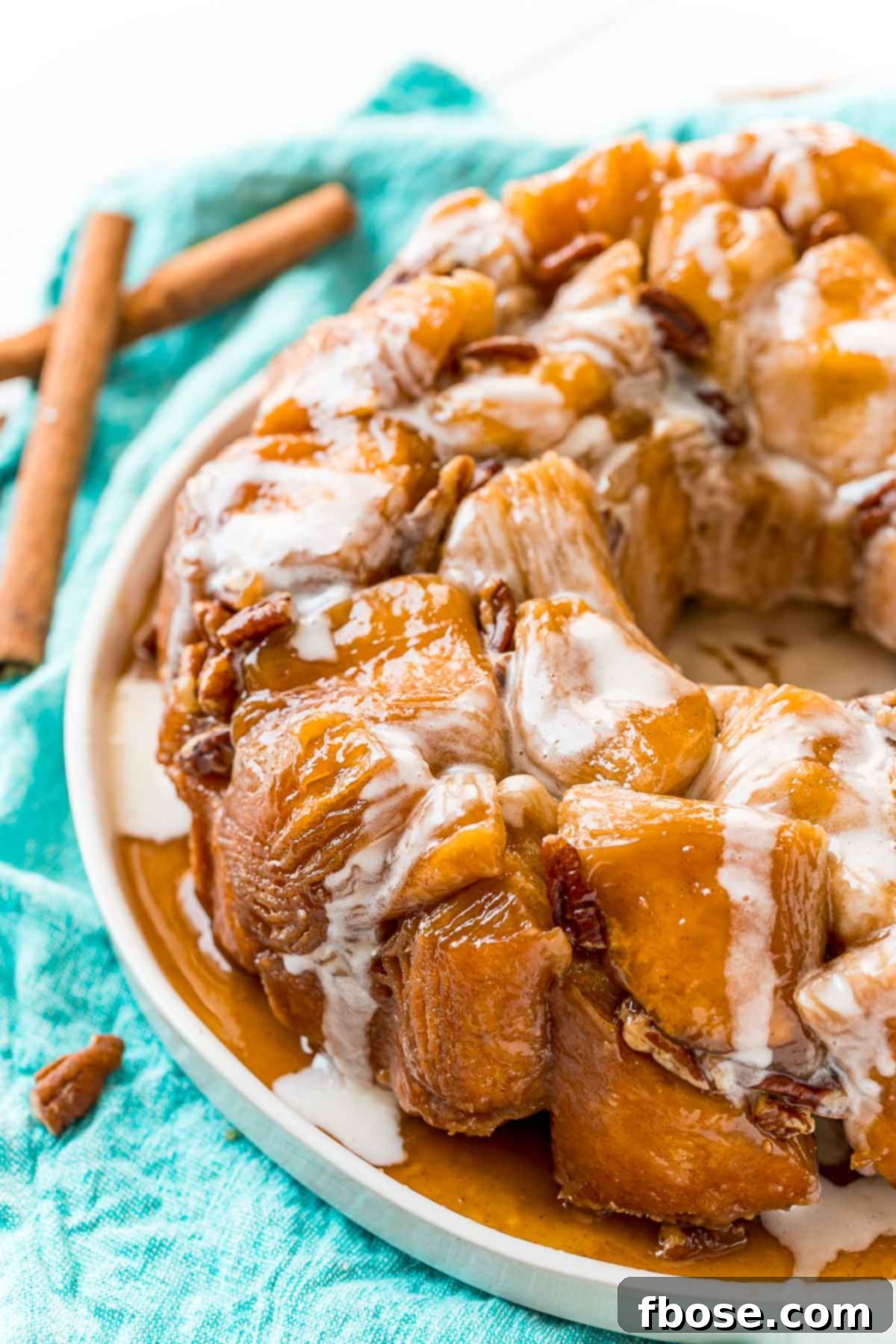 Close up photo of monkey bread on a white plate on a teal napkin.