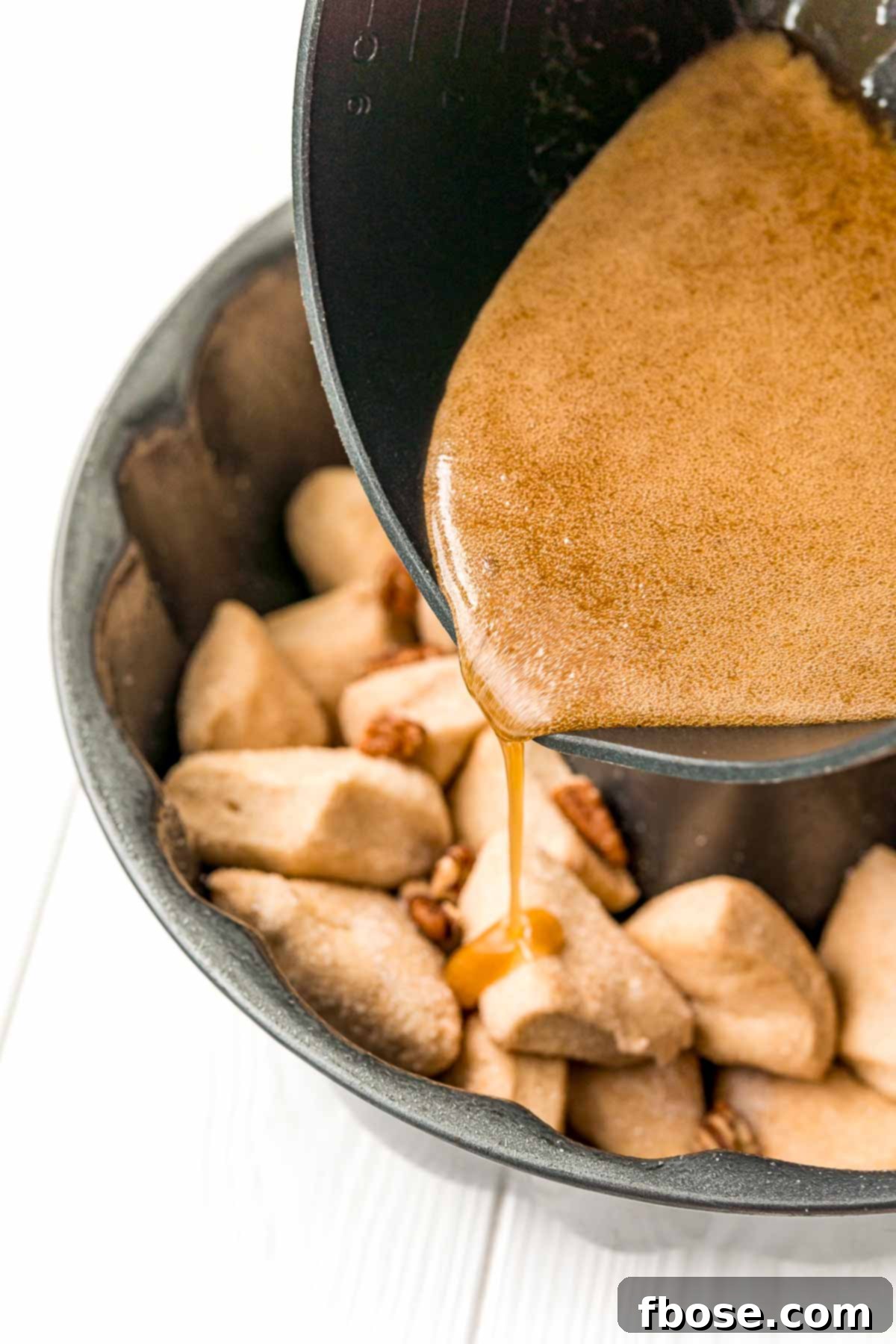 monkey bread sauce being poured into the pan over biscuits.