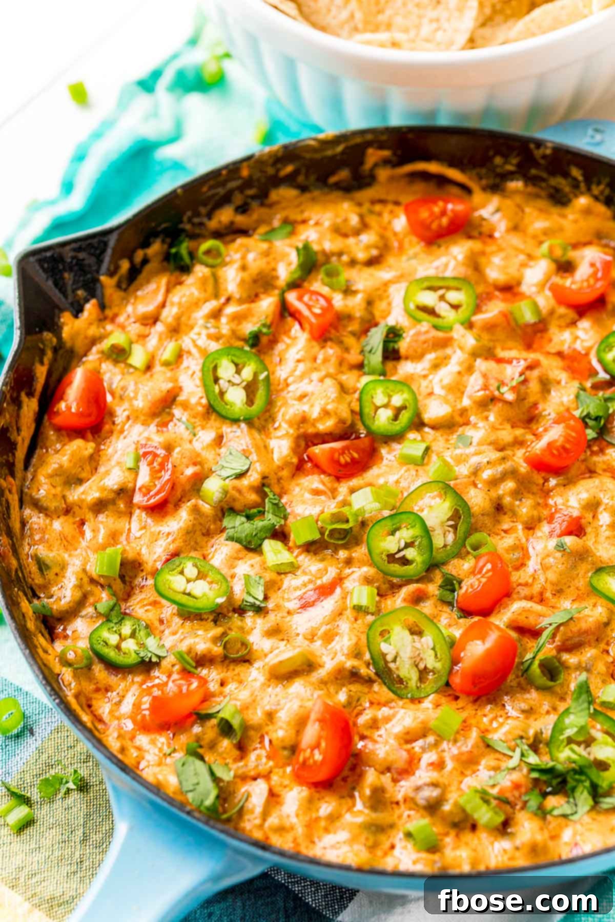 A bubbling cast-iron skillet filled with cheesy sausage dip, ready to be served at a game day party.