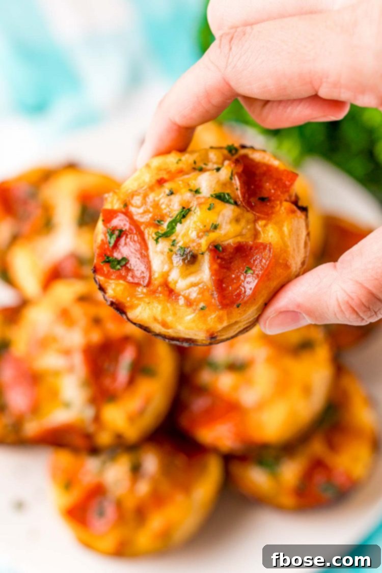 Woman's hand holding a mini pizza.