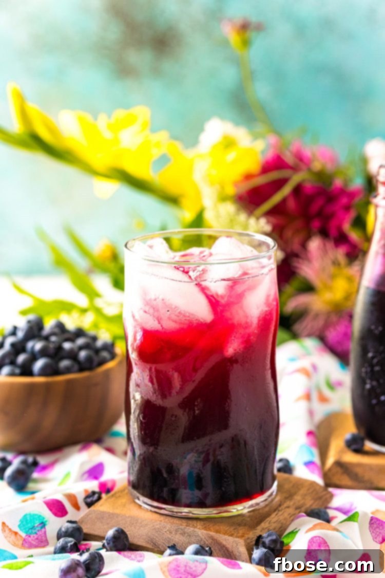 Blueberry Bliss Syrup 3 A glass of vibrant blueberry limeade, made using homemade blueberry simple syrup, garnished with fresh blueberries and lime slices.