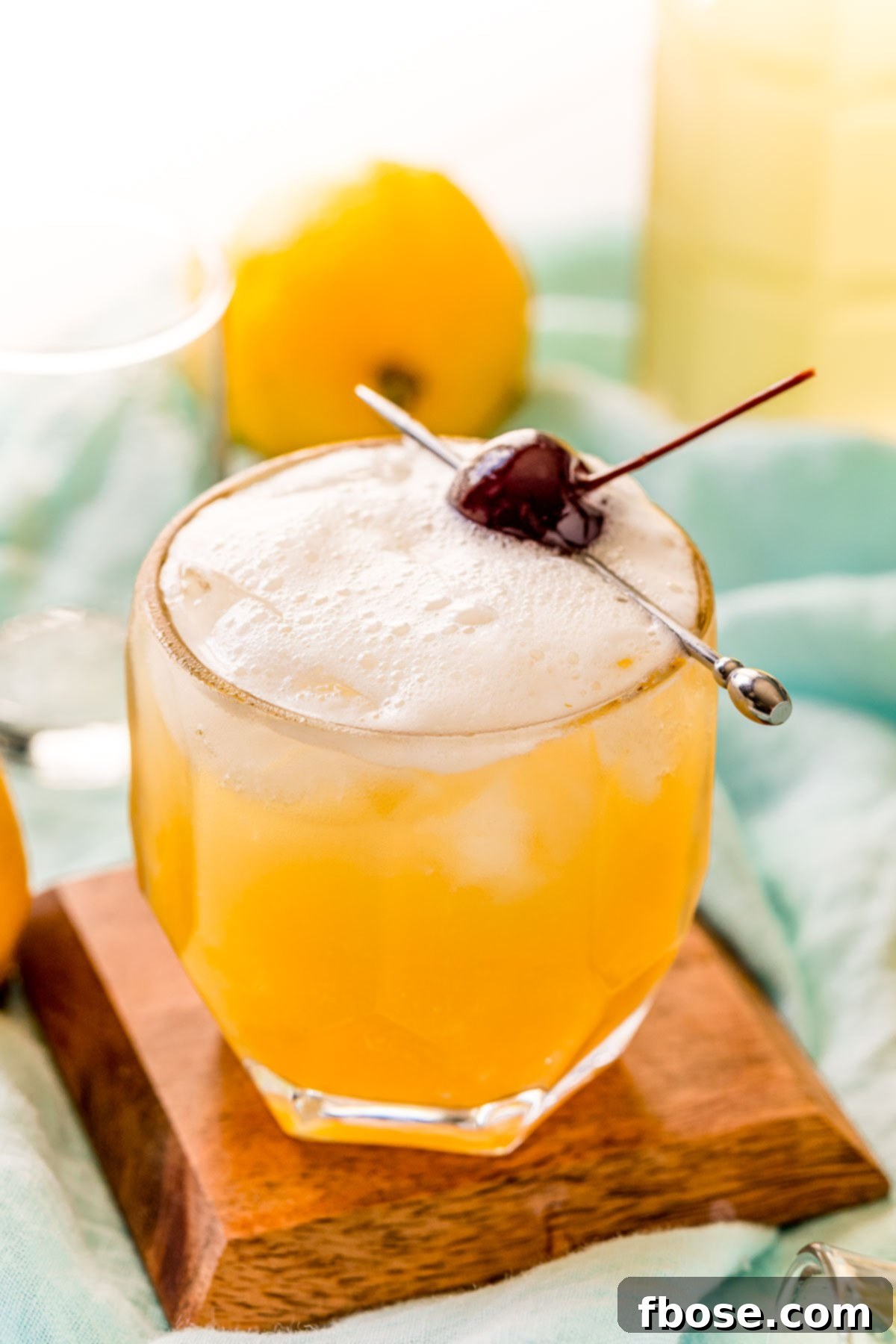 Crafting the Perfect Bourbon Sour 10 Classic Boston Sour recipe on a wooden coaster garnished with a brandied cherry.