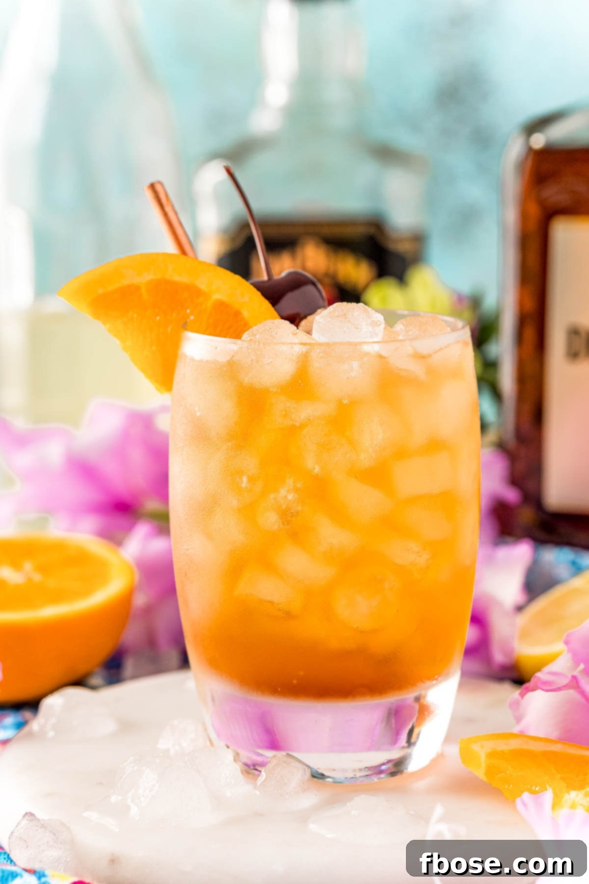 Close up photo of an Amaretto sour garnished with an orange wedge and cherry.
