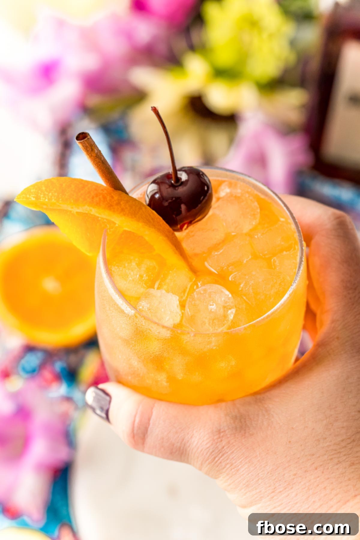 Woman's hand holding an Amaretto Sour up to the camera.