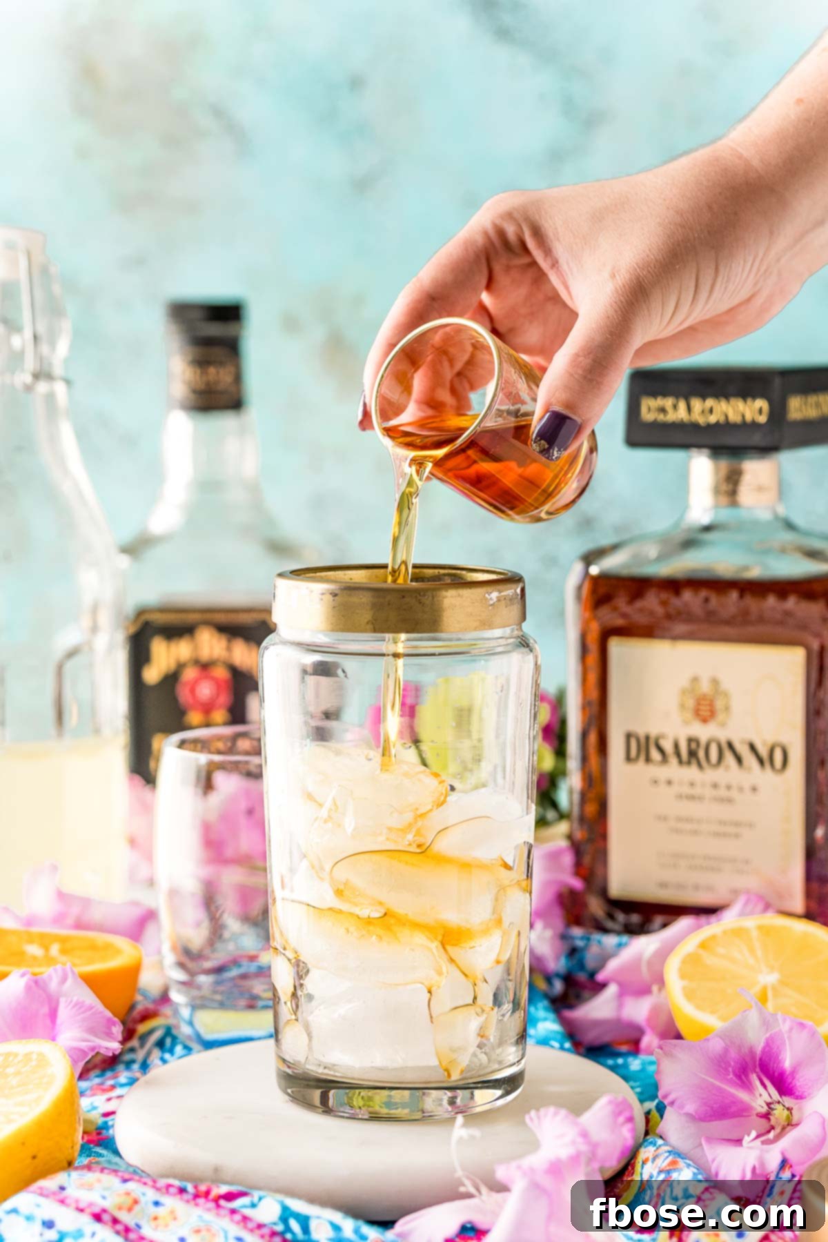 Amaretto being added to a cocktail shaker with ice.