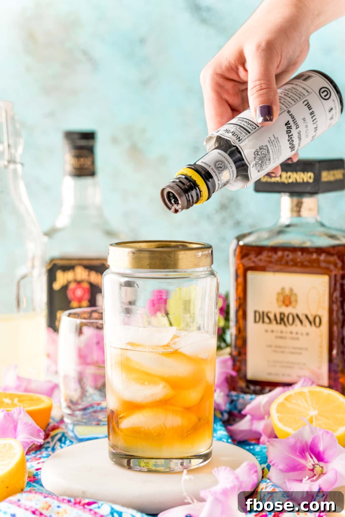Angostura bitters being added to a cocktail shaker.