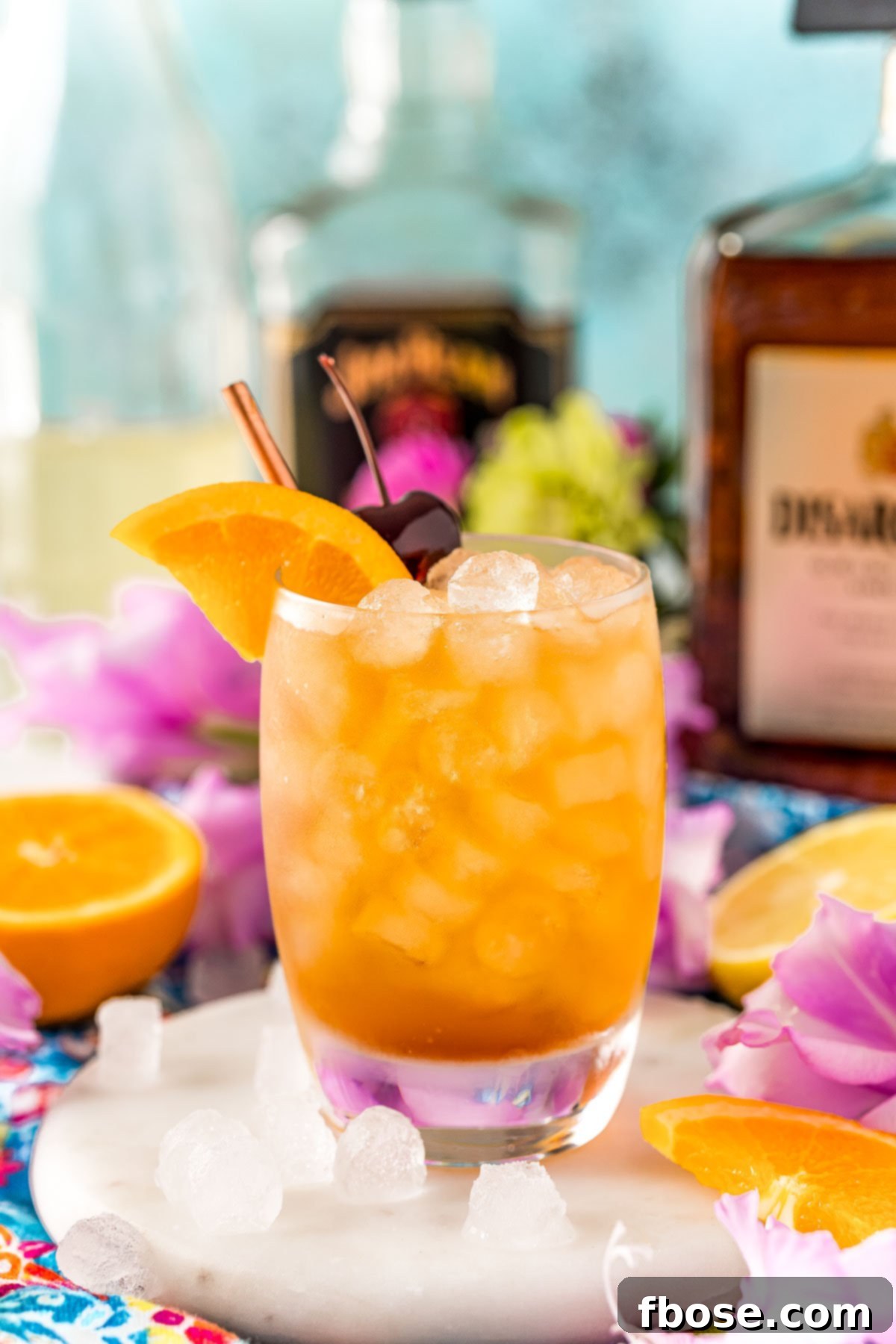 Close up photo of an Amaretto sour garnished with an orange wedge and cherry.