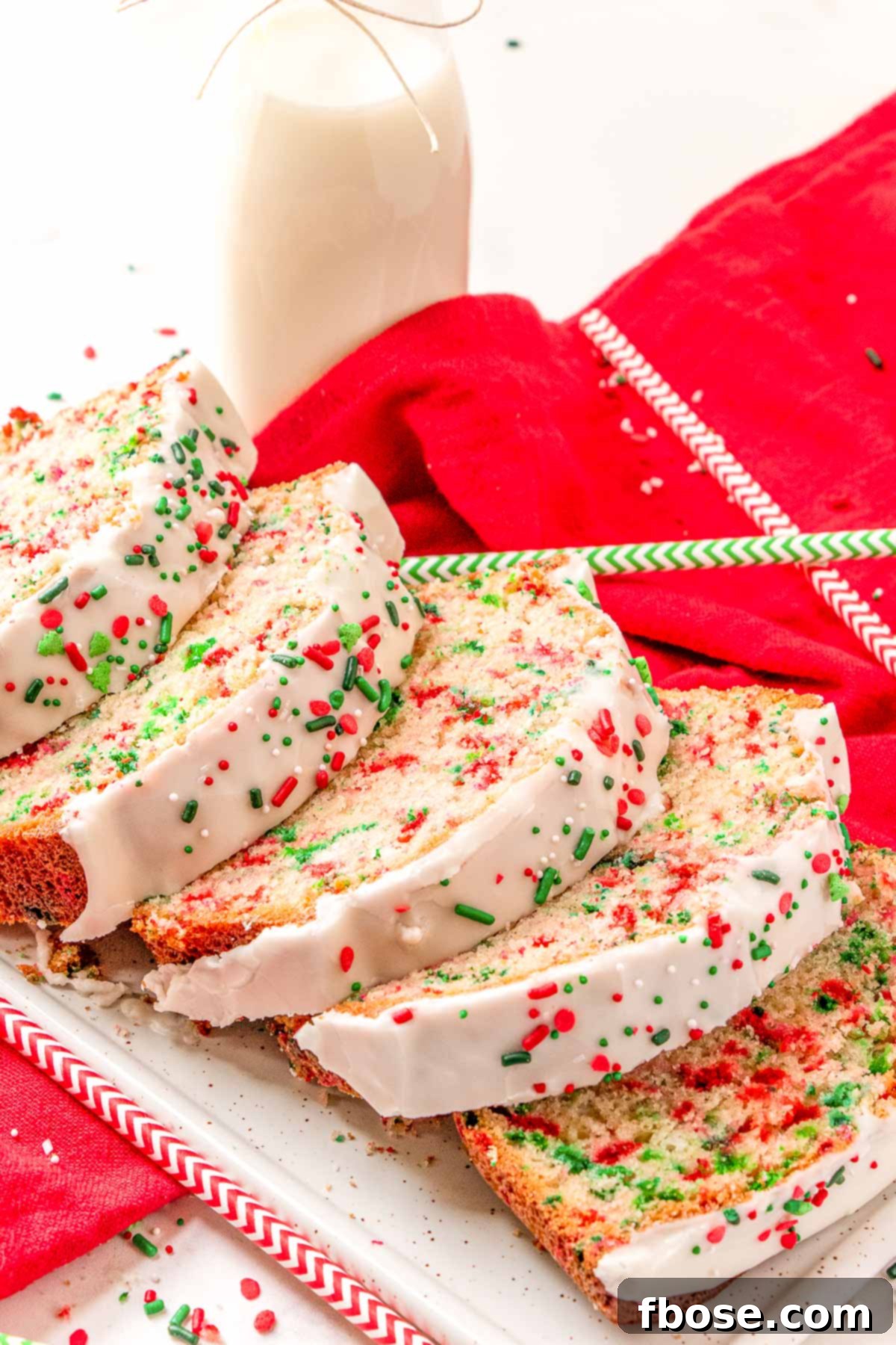 Slices of Christmas Funfetti Bread on a white serving tray, showing the colorful sprinkles throughout.