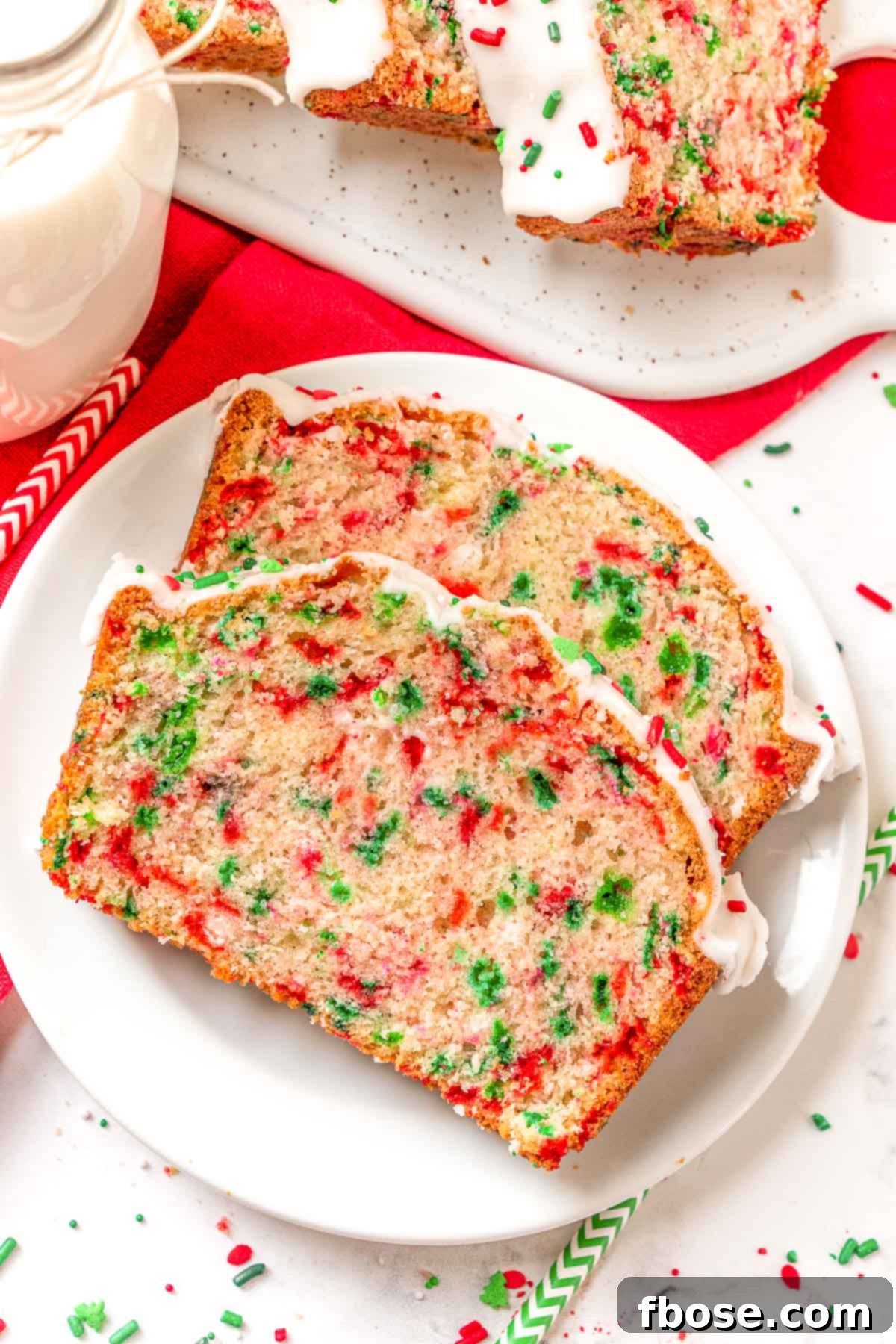 Two slices of Christmas Funfetti Bread on a white plate, highlighting the tender crumb and colorful sprinkles.