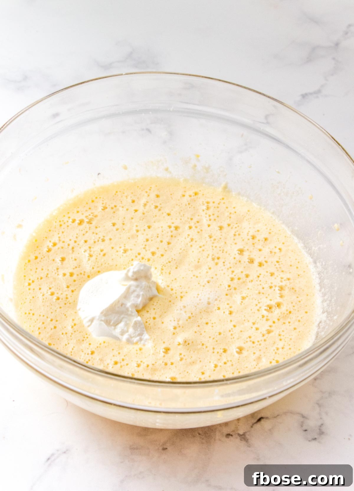 Quick bread batter being made in a glass mixing bowl, showing the creamy wet ingredients.