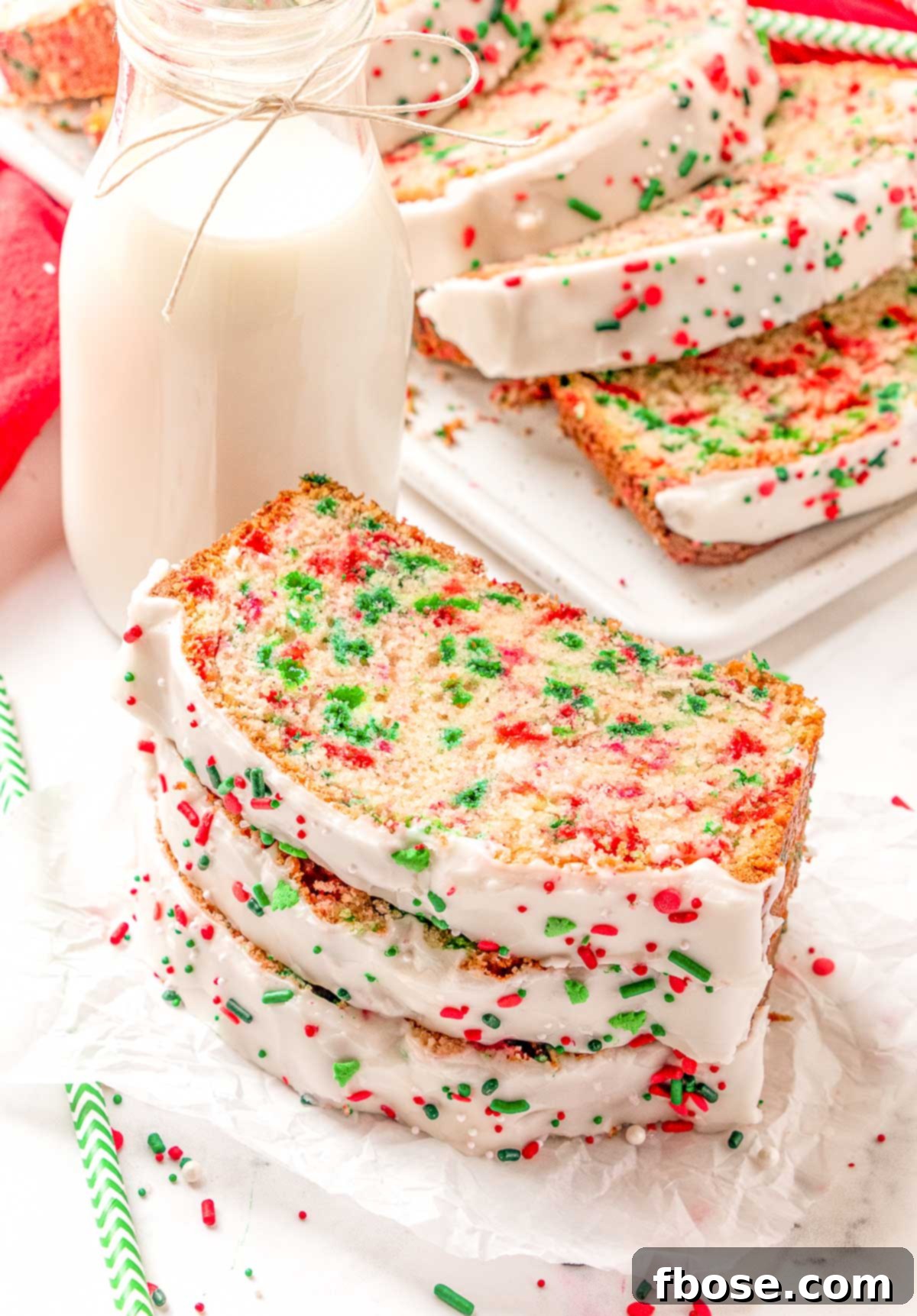 Slices of holiday quick bread on a table with a jug of milk and sprinkles, ready to be enjoyed.