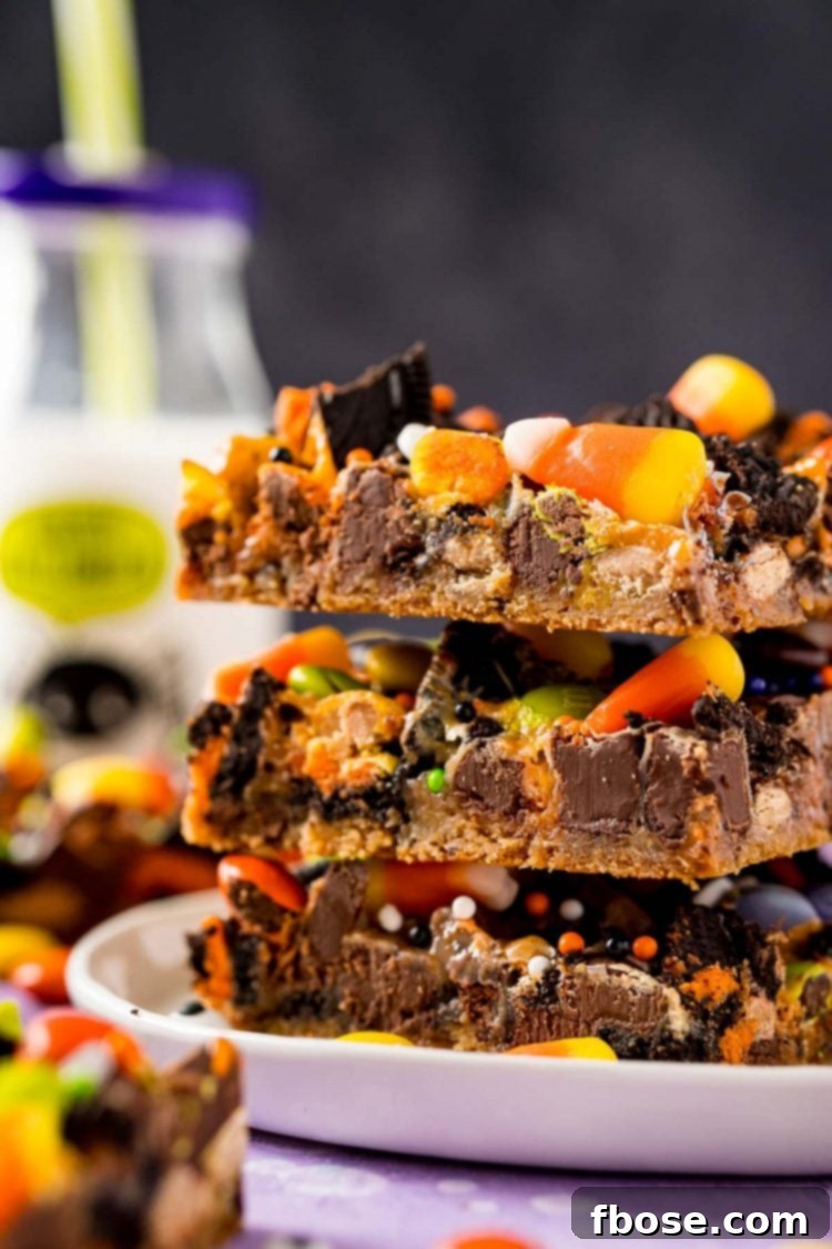 Spellbound Seven-Layer Bars 2 Close up photo of Halloween themed cookie bars on a white plate, stacked three high with a bottle of milk in the background.