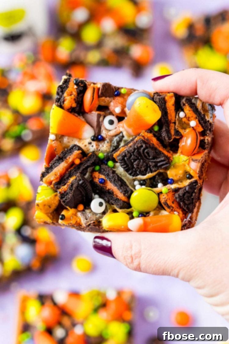 Spellbound Seven-Layer Bars 8 Woman's hand holding a halloween cookie bar towards the camera.