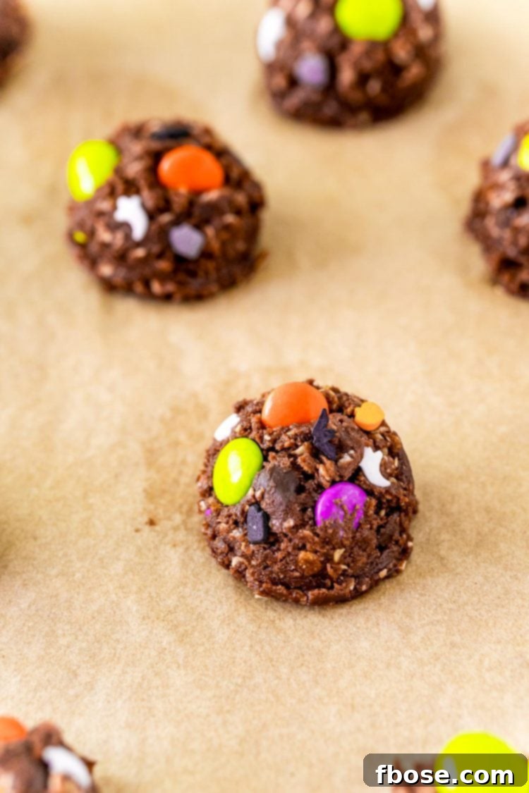 Balls of chocolate cookies dough with halloween sprinkles on parchment paper.